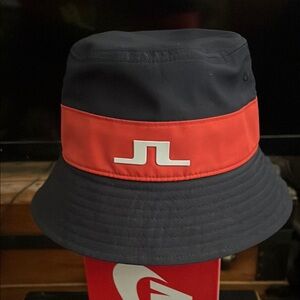 J.LINDEBERG DEACON BUCKET HAT NAVY WITH RED/CORAL BAND